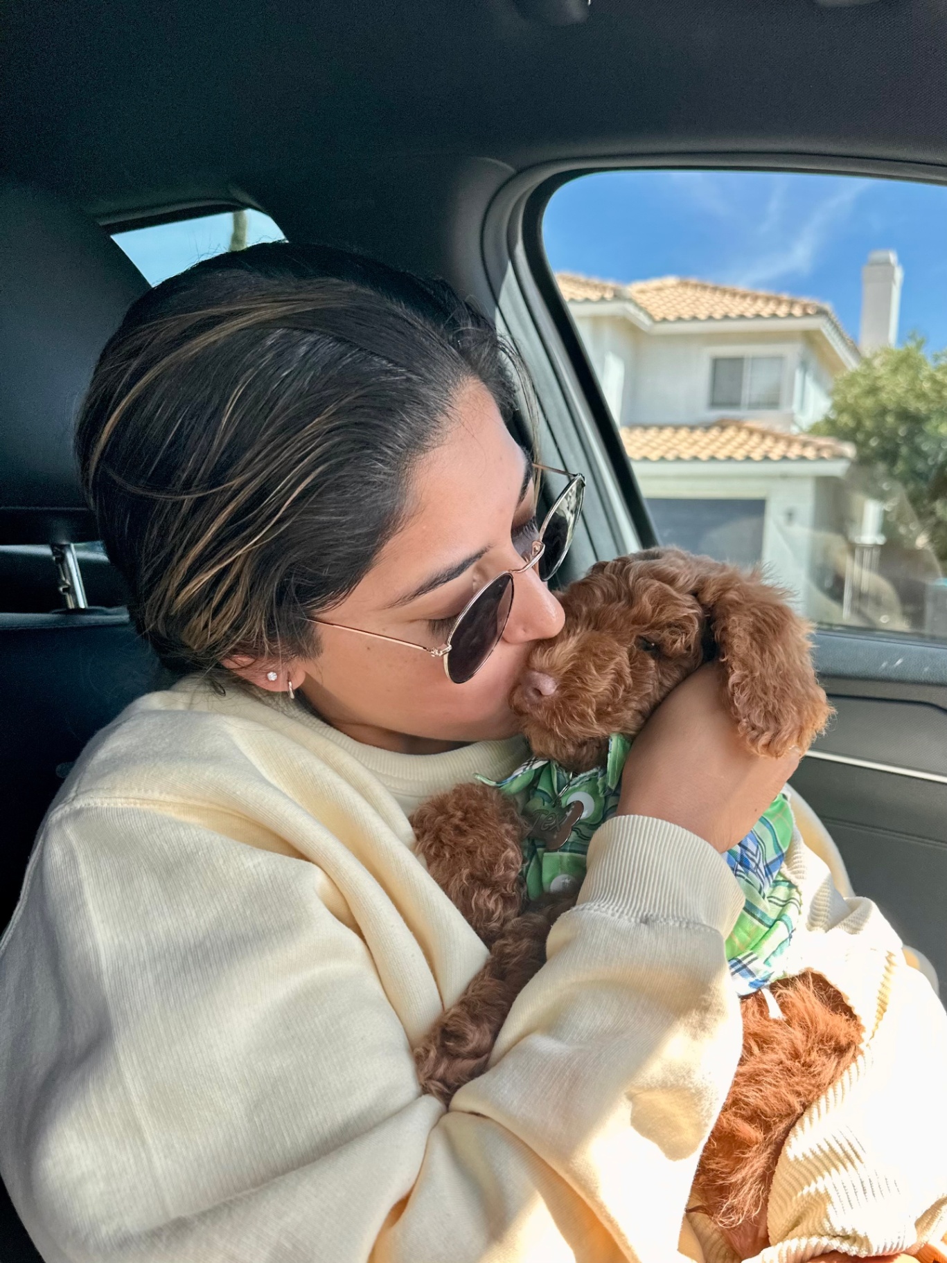 A new family kissing their Kid's Best Doodle Goldendoodle puppy in the car on the way home